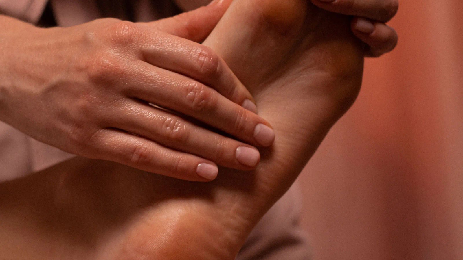 Mains de la praticienne massant un pied lors d’une séance